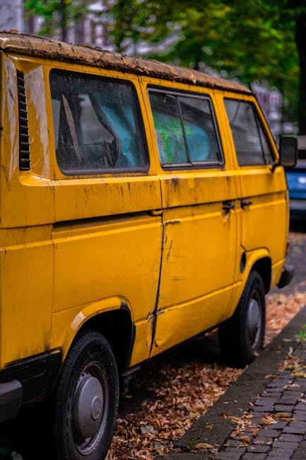 A dark red flatbed utility vehicle parked on an urban street shows an open bed loaded with various domestic rubbish items, including large black and white plastic bags, some filled with waste, and loo